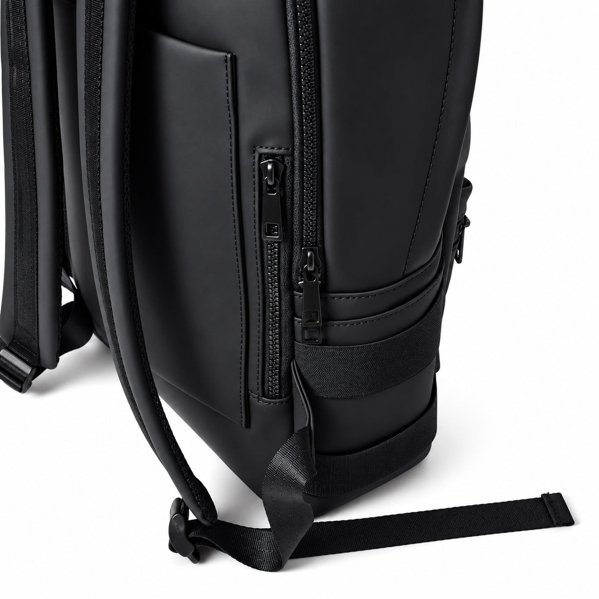 Close view of the black backpack's side webbing, zippers and shoulder strap.