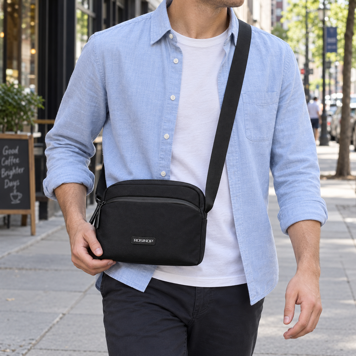Man carrying the black ROSINOP crossbody bag on a city sidewalk.