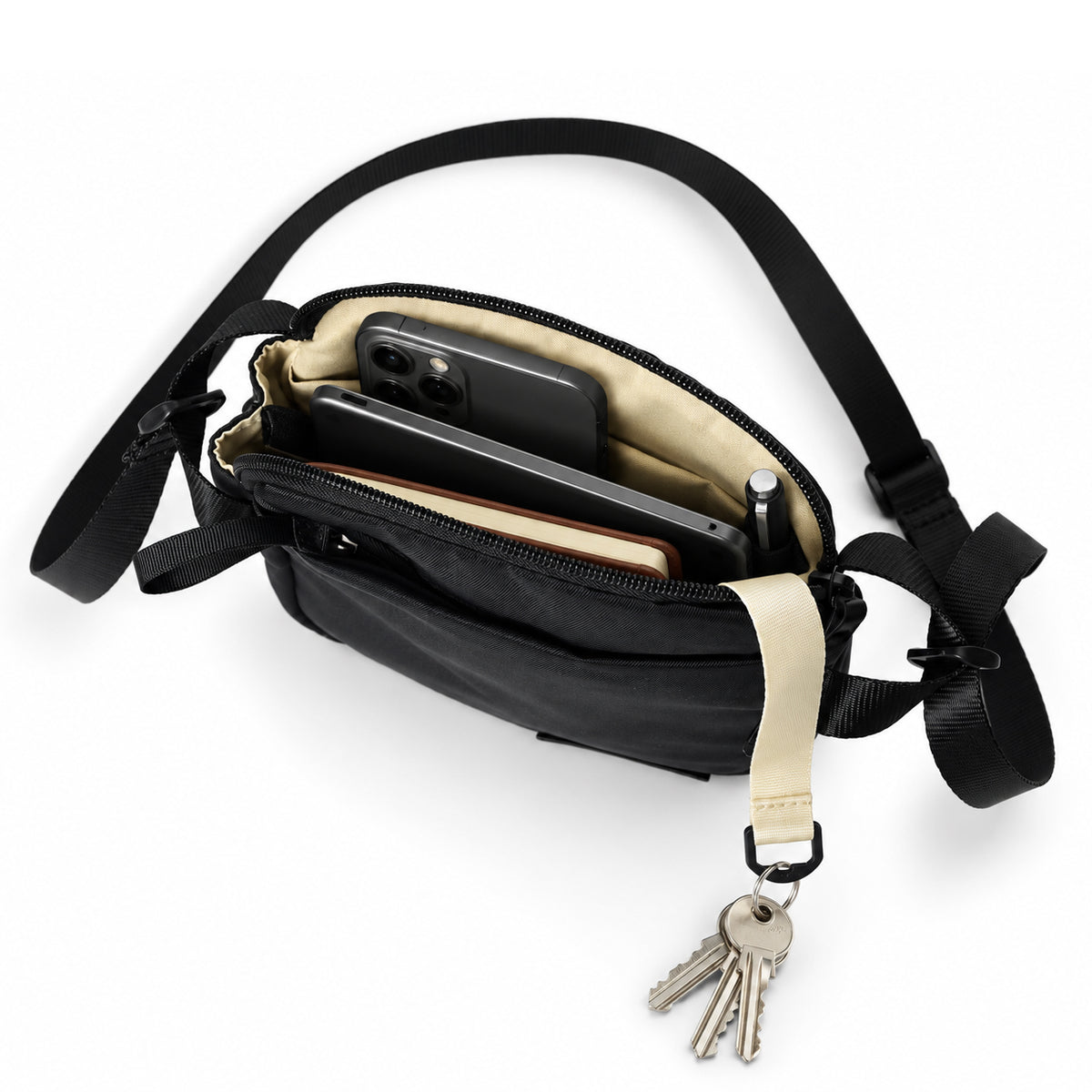 Open compact crossbody bag with beige lining and key leash.