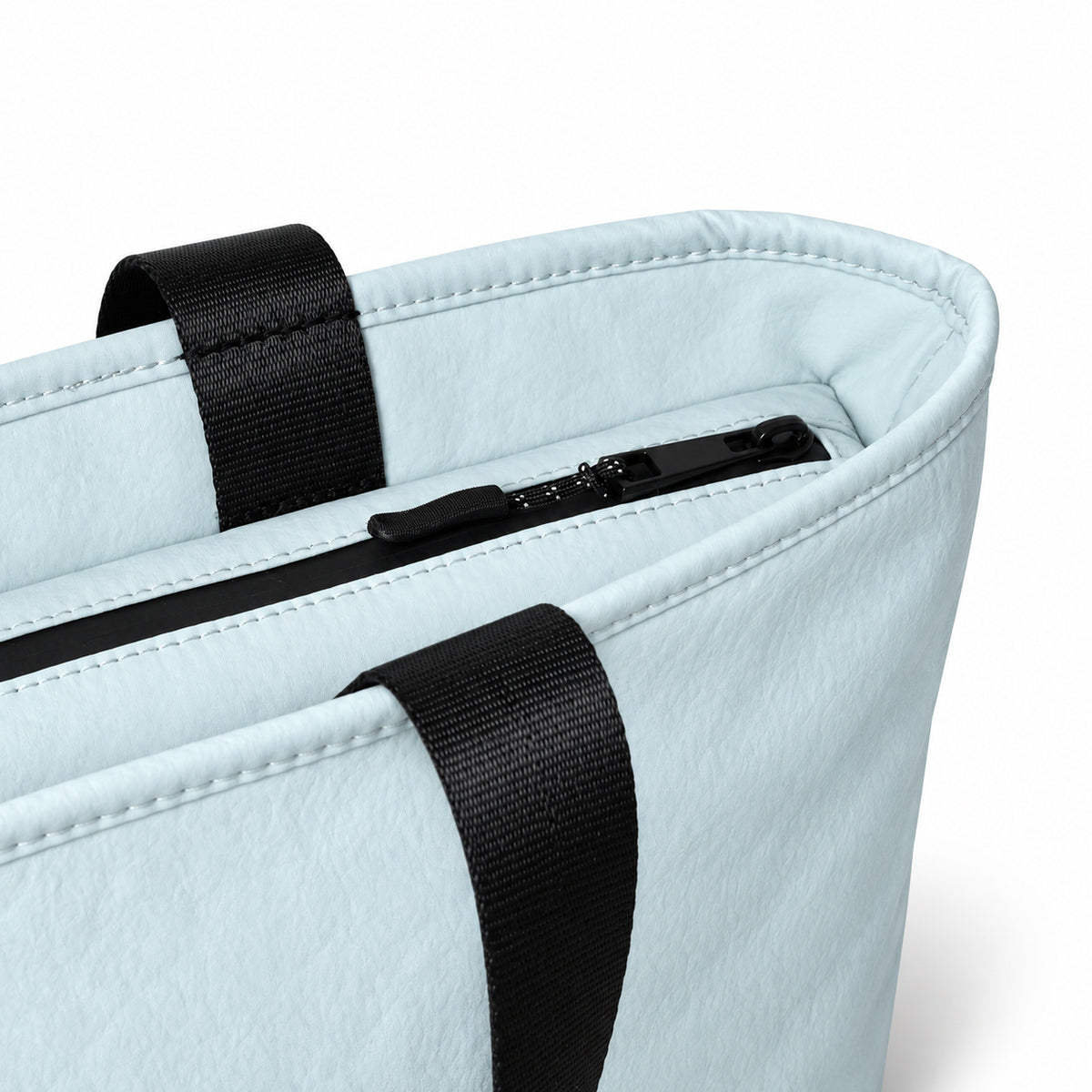 Close-up of the light blue tote zip closure and stitched carry handles.