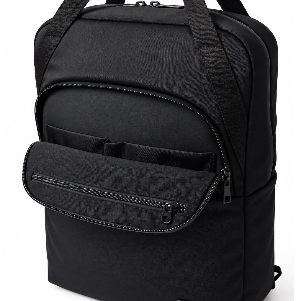 Front view of the black tote backpack with long carry handles and a curved front zip pocket.
